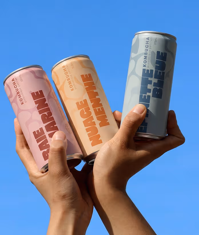 image generated by adobe firefly -Two hands holding three kombucha cans labeled Baie Marine, Nuage Menthe, and Lierre Bleue against a blue sky.