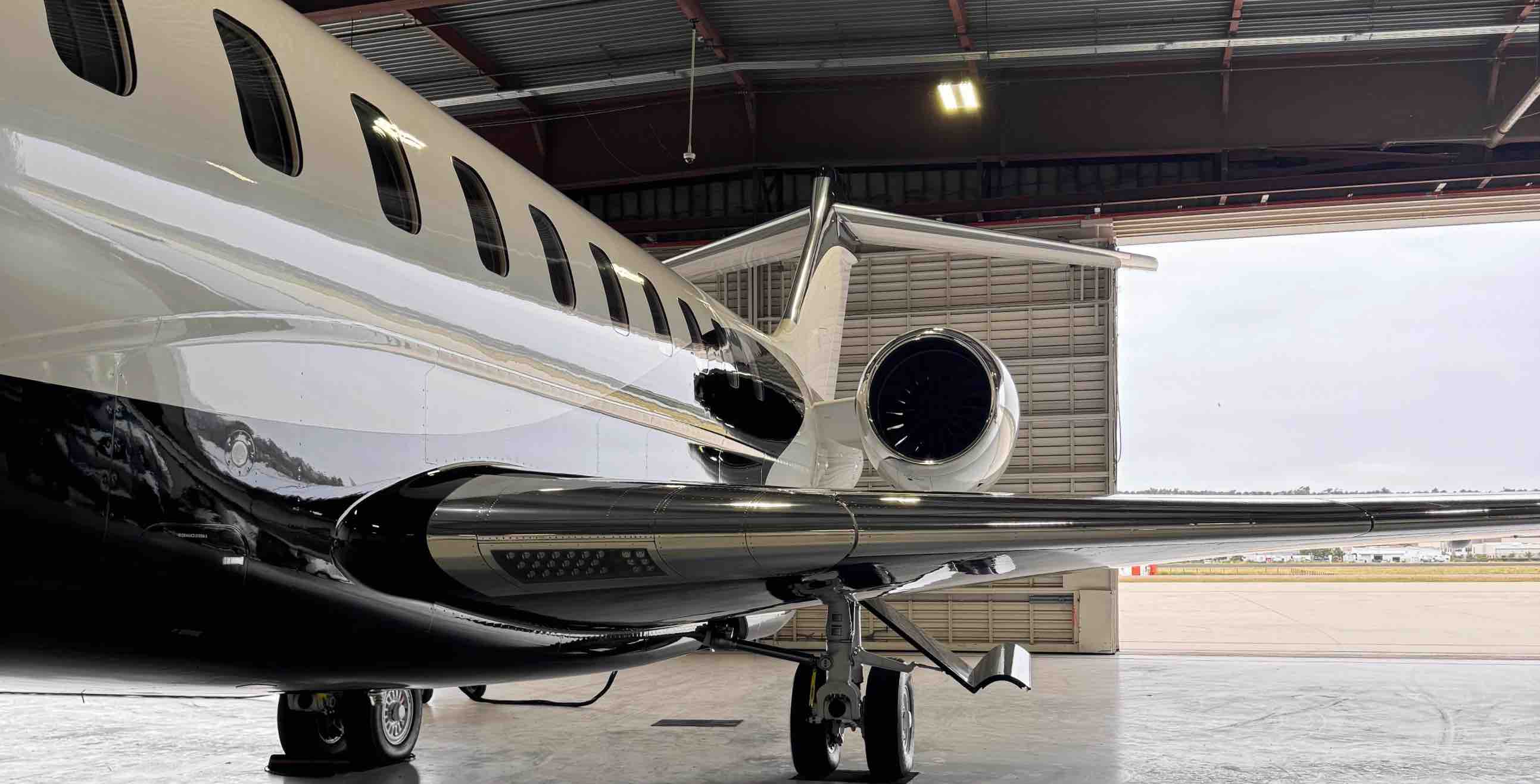 Rear side of a sleek private jet inside a hangar with landing gear visible.