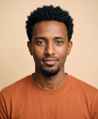 Portrait of a man with short curly hair and a goatee wearing a rust-colored T-shirt.