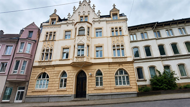 Historische Häuserfassaden mit verzierten Giebeln und hohen Fenstern.