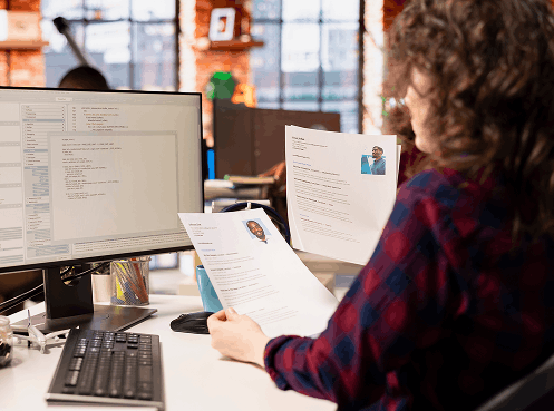 Recruiter reviewing printed resumes with candidate photos