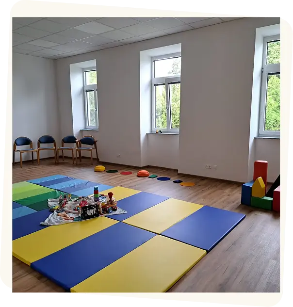 Heller Raum für den Baby-Treff mit bunten Spielmatten, Bausteinen und Spielzeug in Stockerau