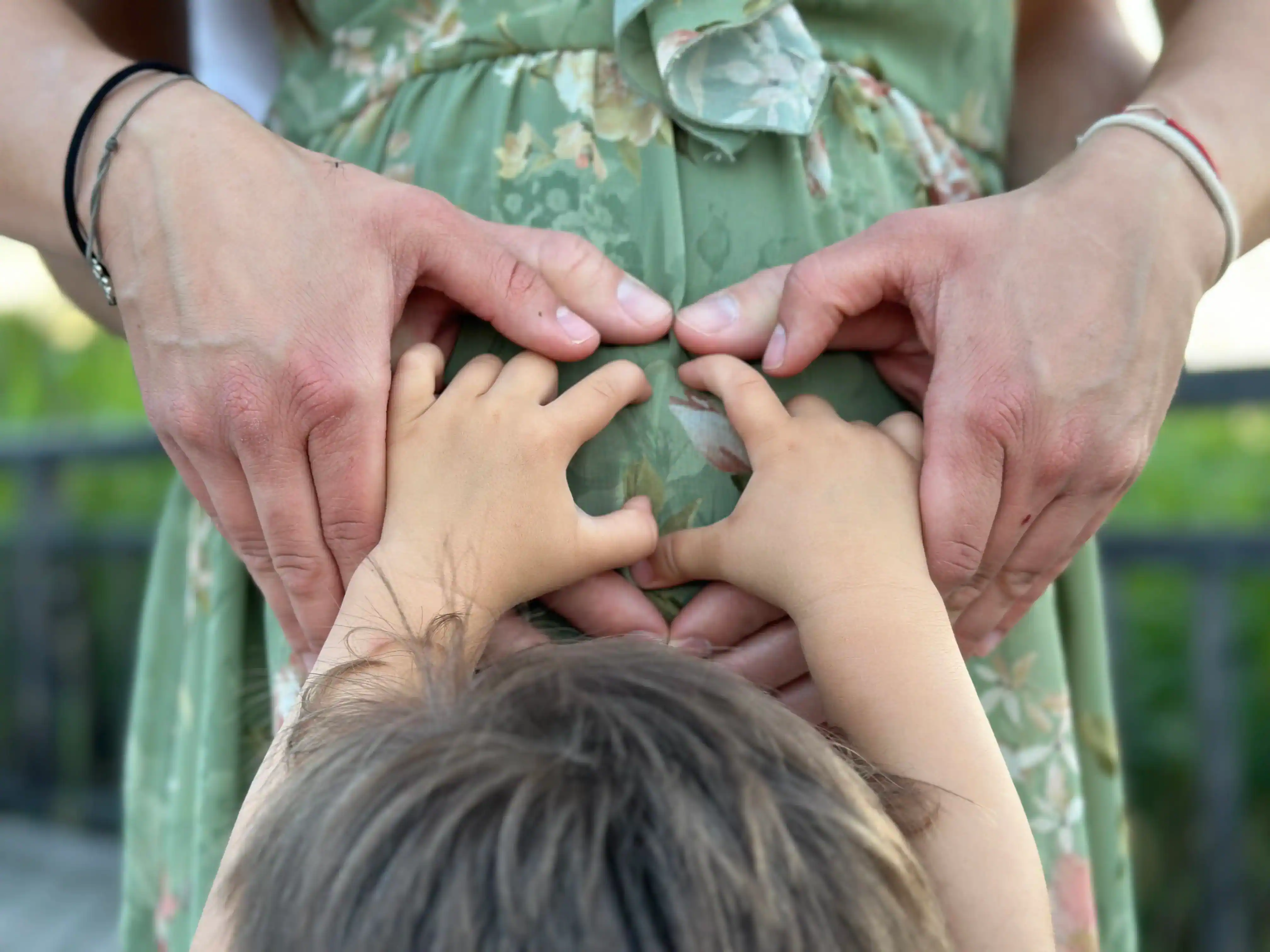 Familie mit Geschwisterkind, Hand auf dem Babybauch der Schwangeren
