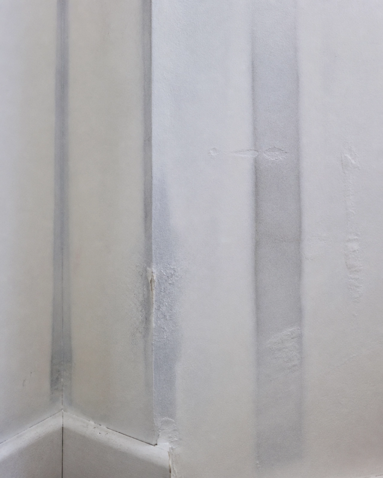 Macro detail of ghosting shadows on a plasterboard wall indicating thermal bridging and moisture