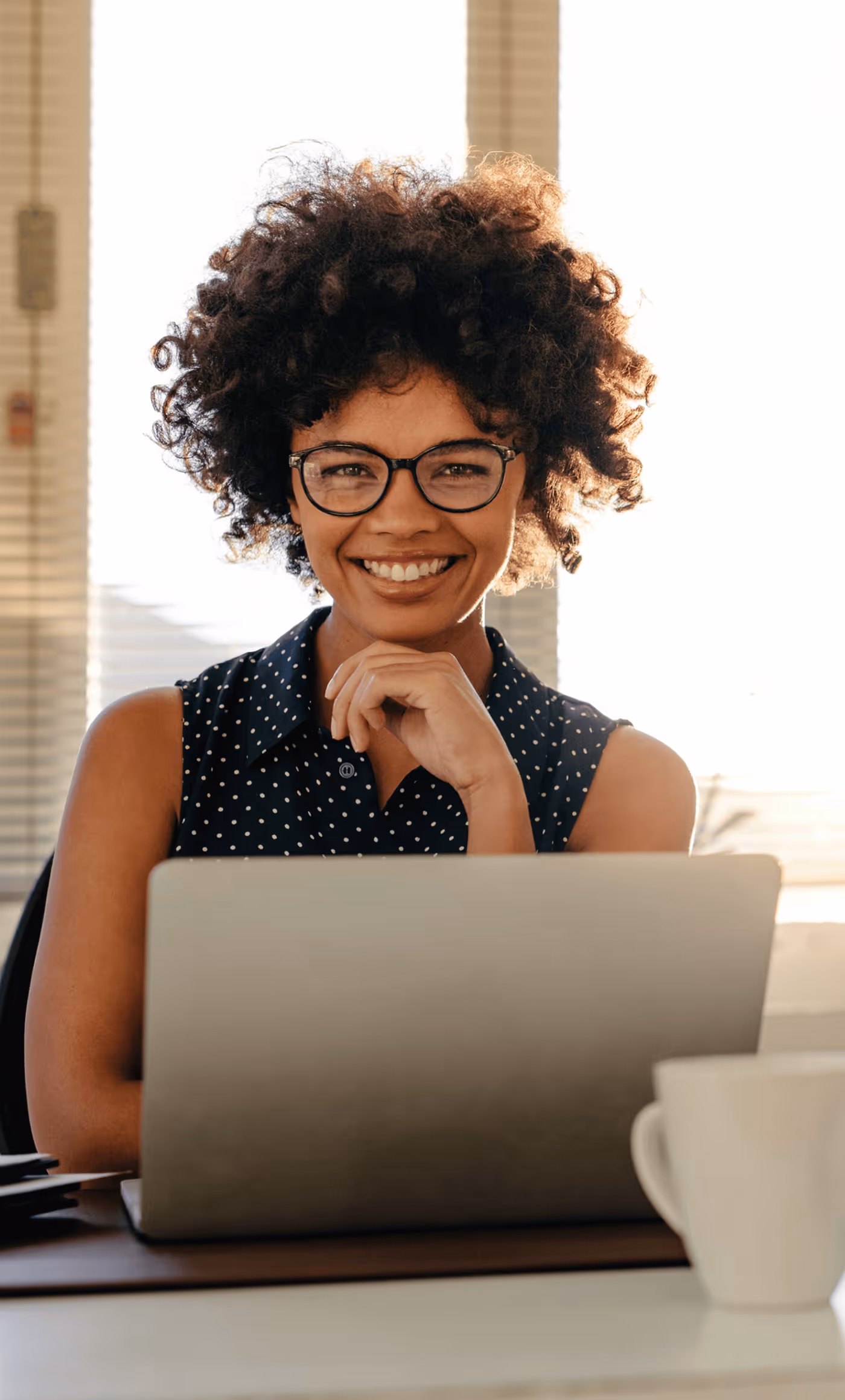 A Smiling Woman Sitting Behind a Laptop - Photo