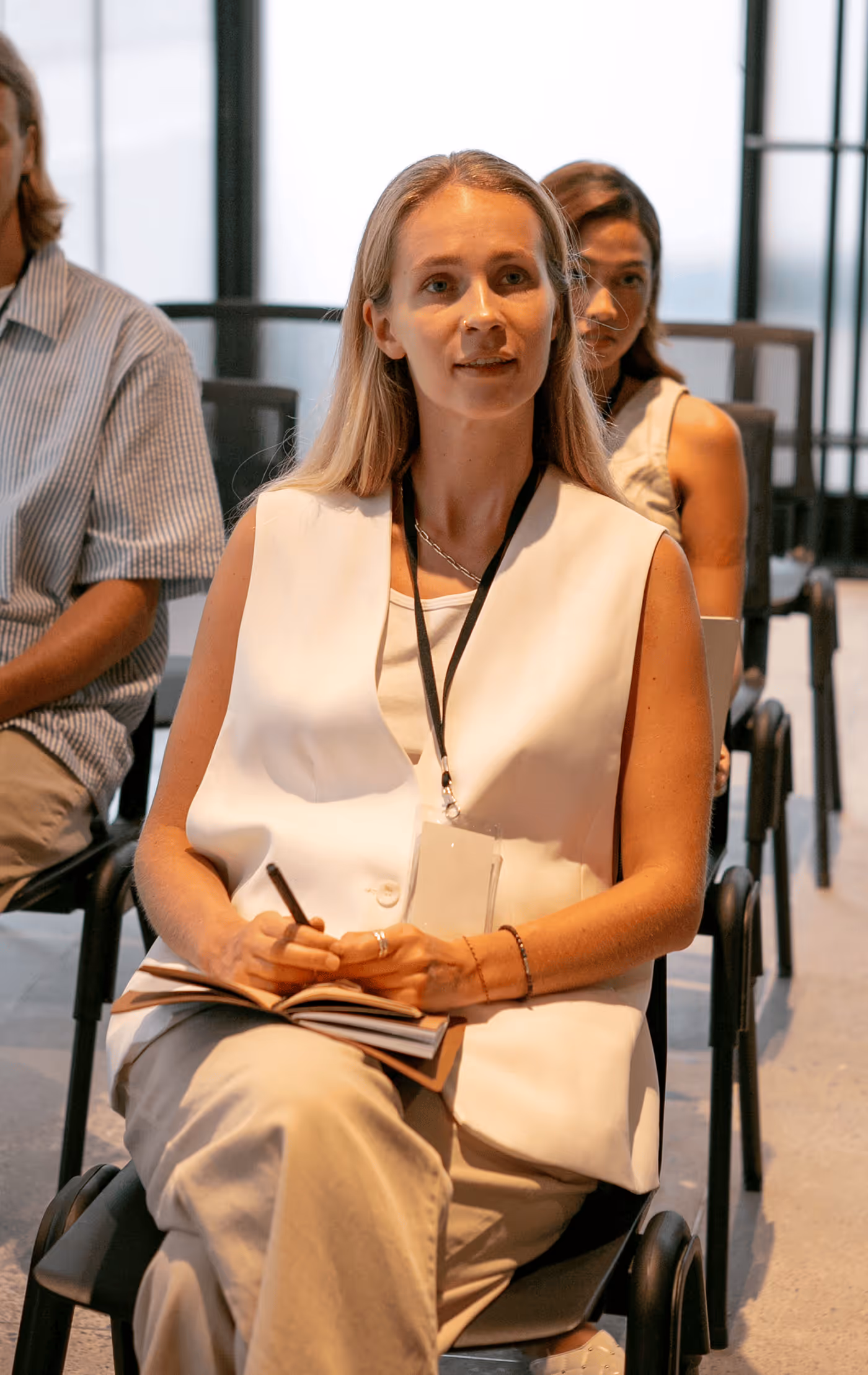 A Woman Sitting in an Audience Listening - Photo