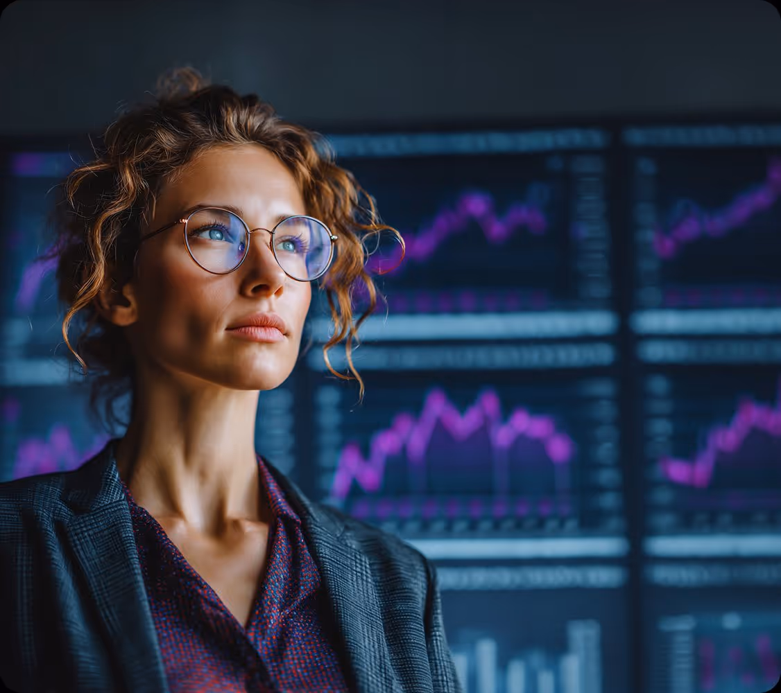 Woman with glasses looking thoughtful in front of screens showing purple financial charts and graphs.