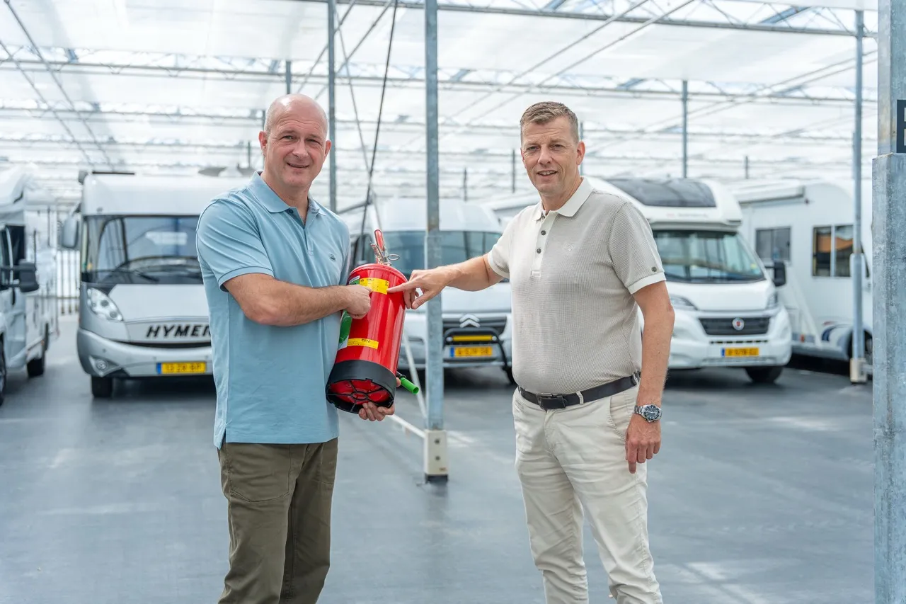 Adviseur van Satter Assurantiën en ondernemer met een brandblusser tussen de campers in een stalling