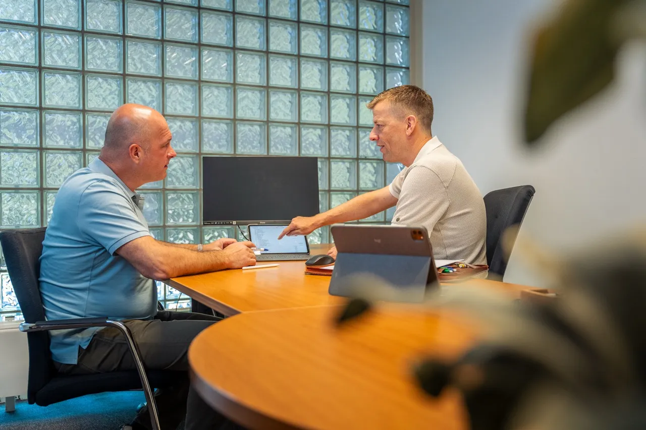 Twee medewerkers van Satter Assurantiën overleggen samen achter de laptop