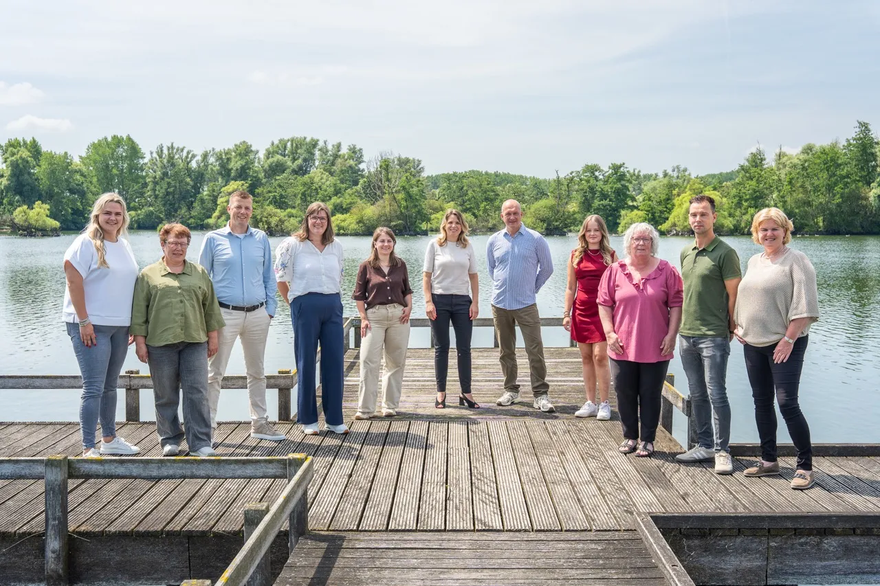 Groepsfoto van het team van Satter Assurantiën op een steiger aan het water
