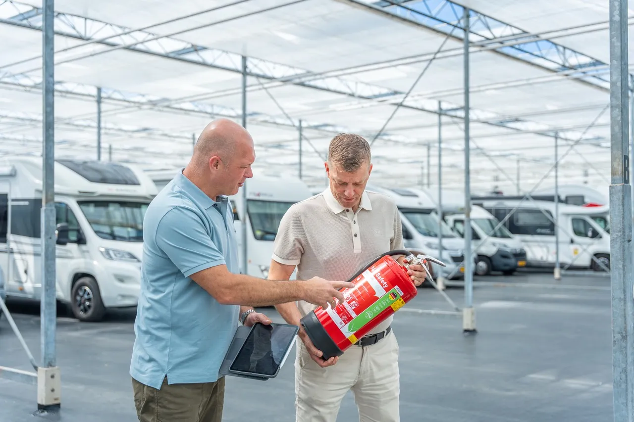 Adviseur en ondernemer controleren een brandblusser in een camperstalling