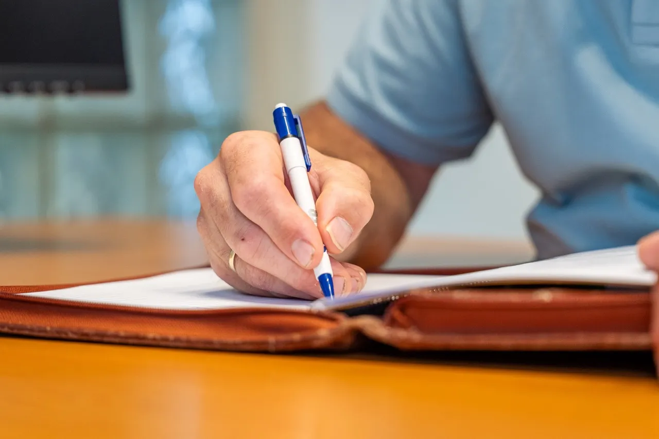 Klant zet een handtekening onder verzekeringsdocumenten bij Satter Assurantiën