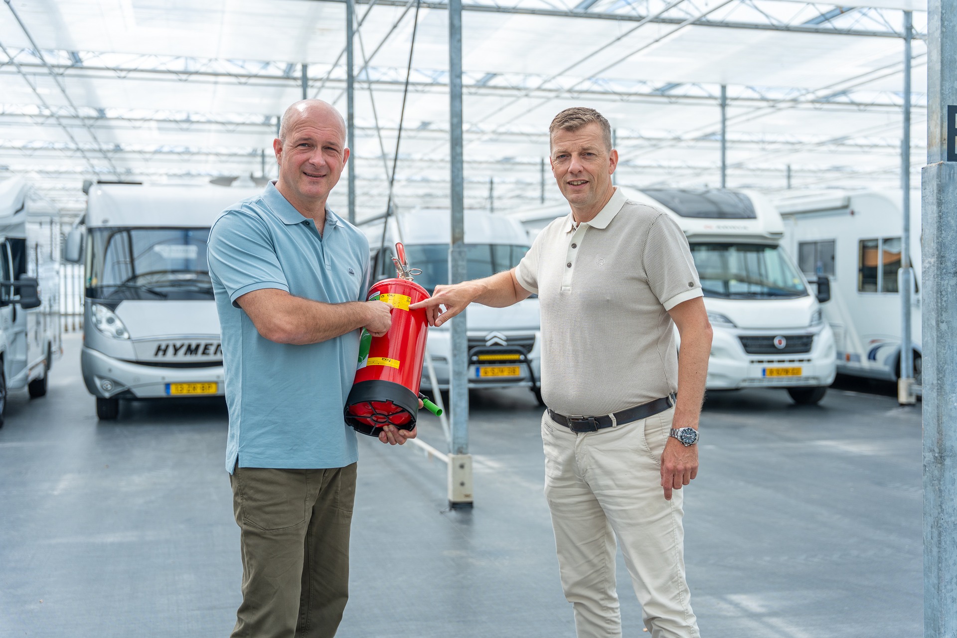 Adviseur van Satter Assurantiën en ondernemer met een brandblusser tussen de campers in een stalling