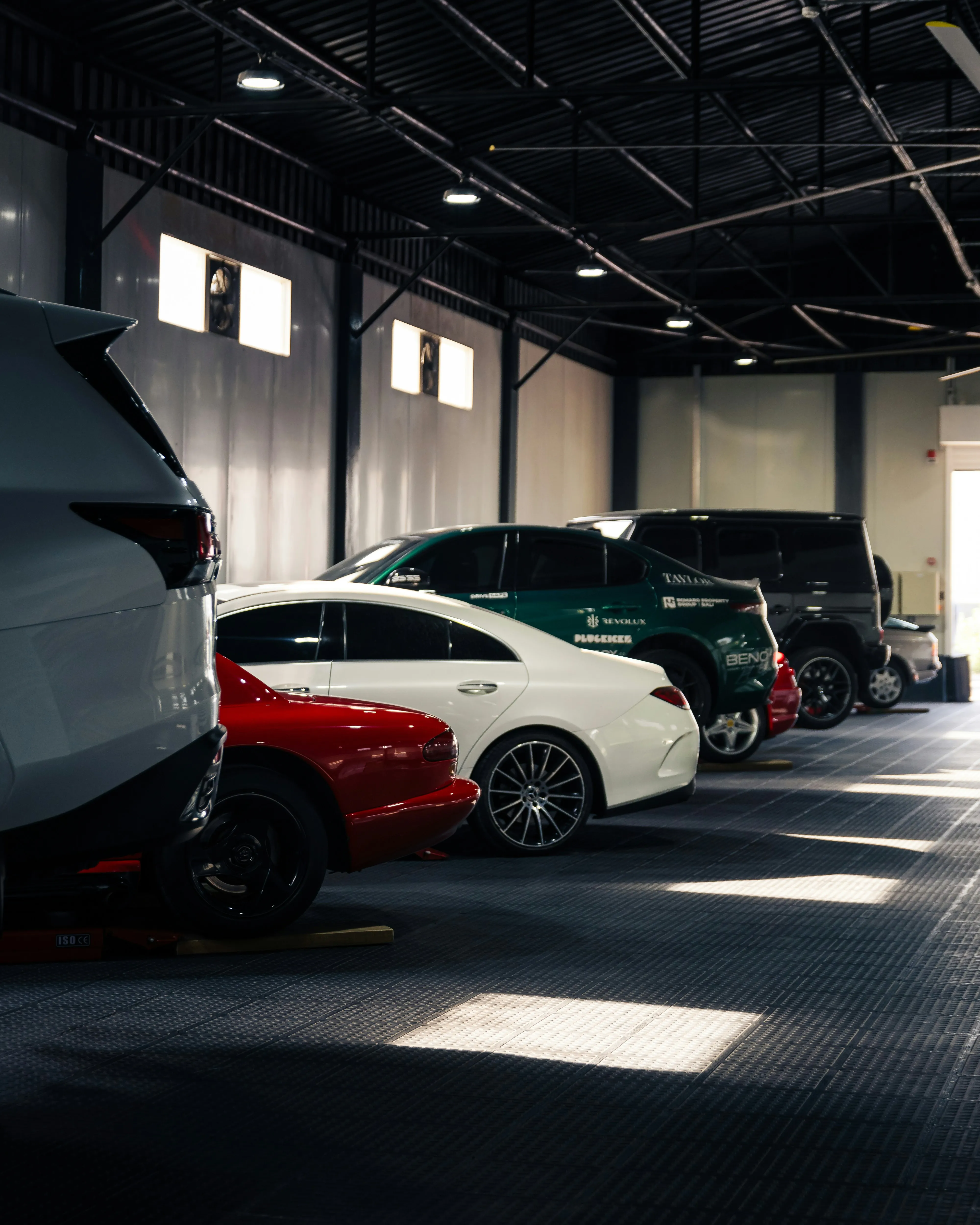 Reihe von geparkten Autos in einer gut beleuchteten, modernen Werkstatt mit Fensterlicht.