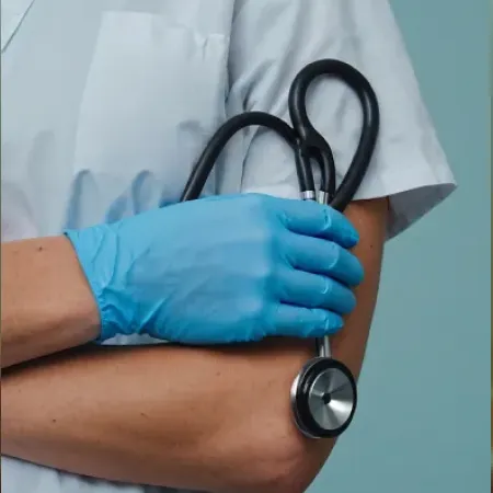 Medical professional with blue gloves holding a black stethoscope against a blue background.