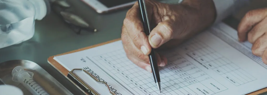 Senior hands holding a pen and filling out a medical report form on a clipboard.
