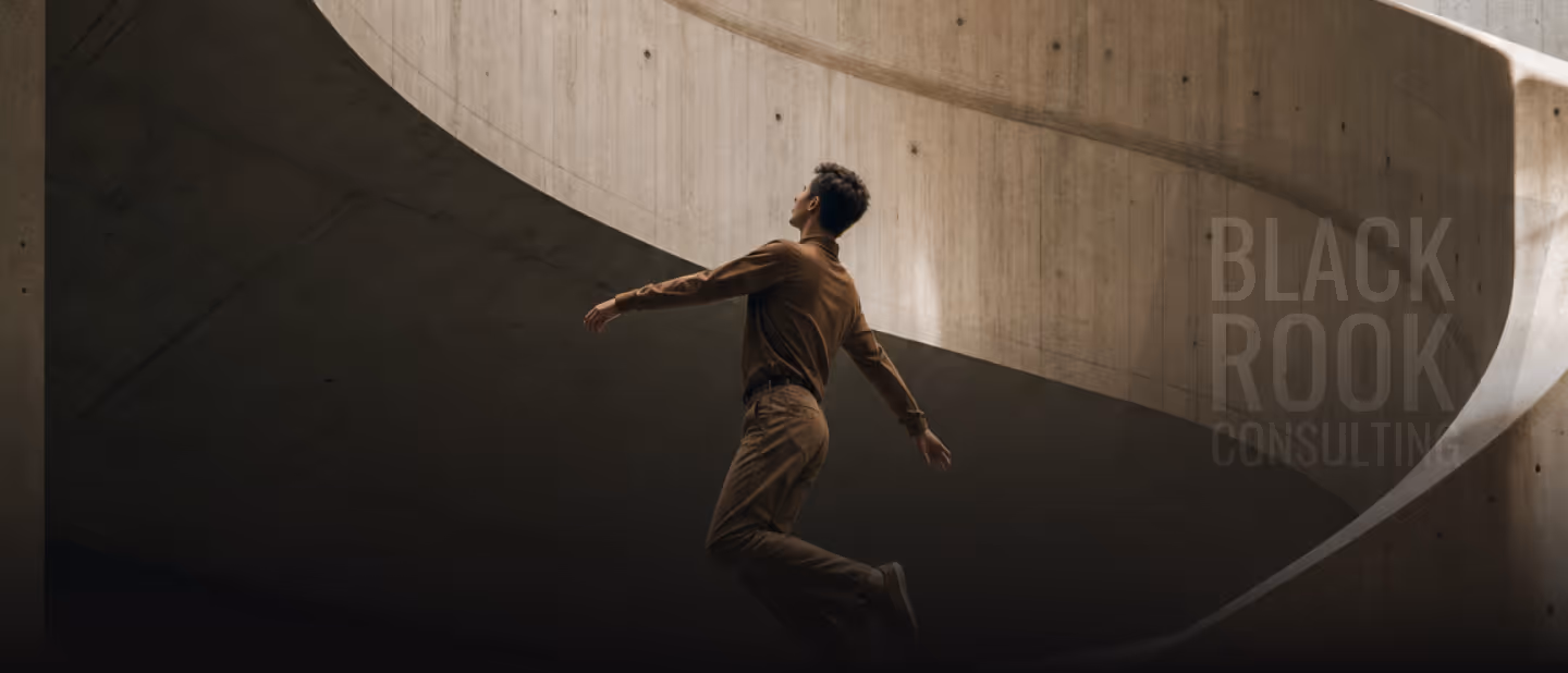 Person in brown clothes walking along a curved concrete architectural structure under soft light.