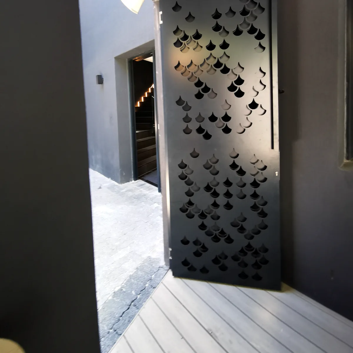 Bespoke perforated aluminium door with a fish-scale pattern, made by TILT Screens