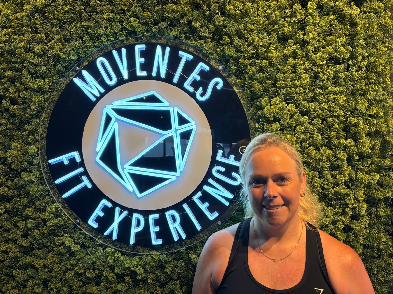 Cindy bij het logo van Moventes Fit Experience in IJsselstein