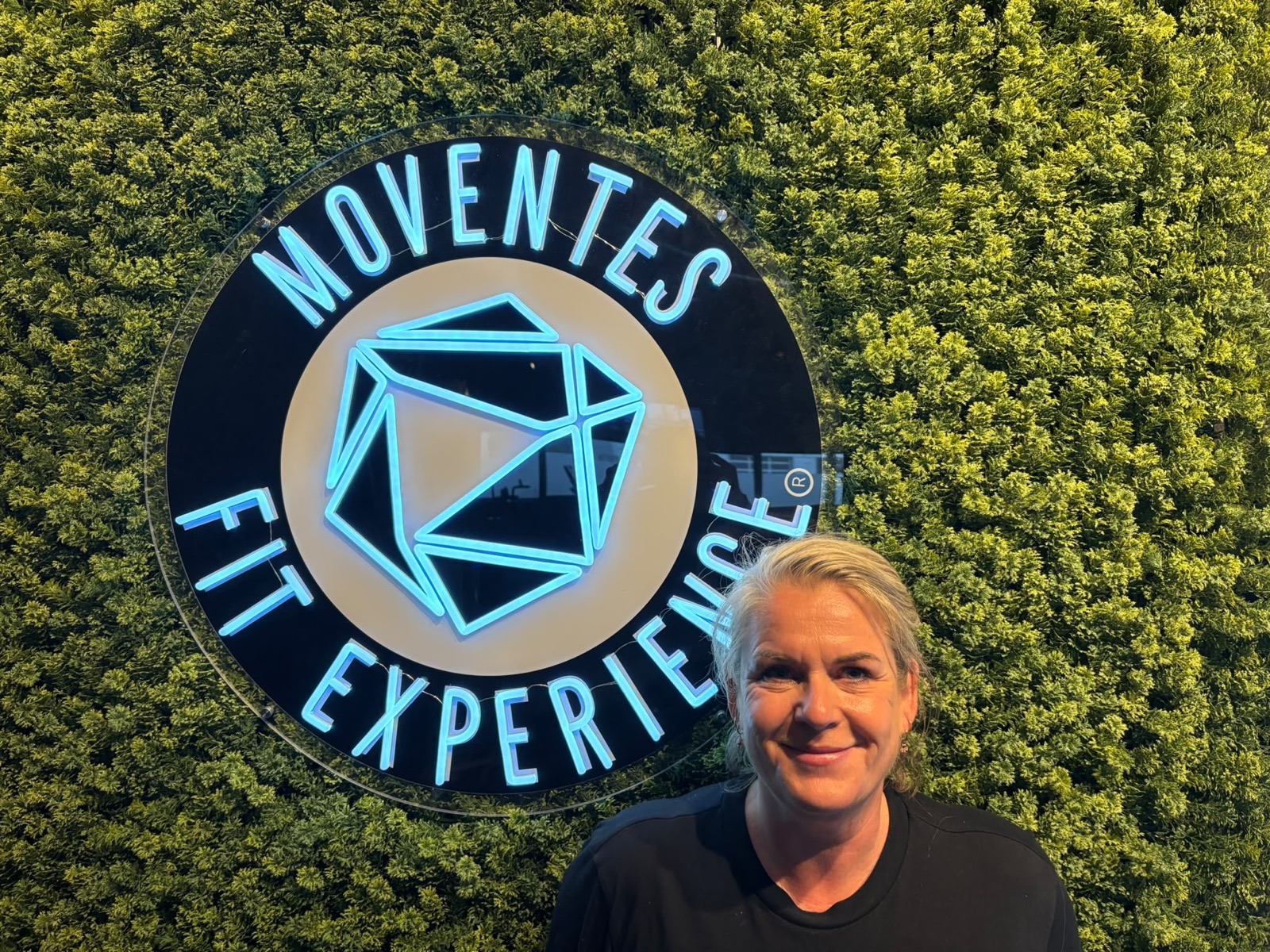 Petra bij het logo van Moventes Fit Experience in IJsselstein
