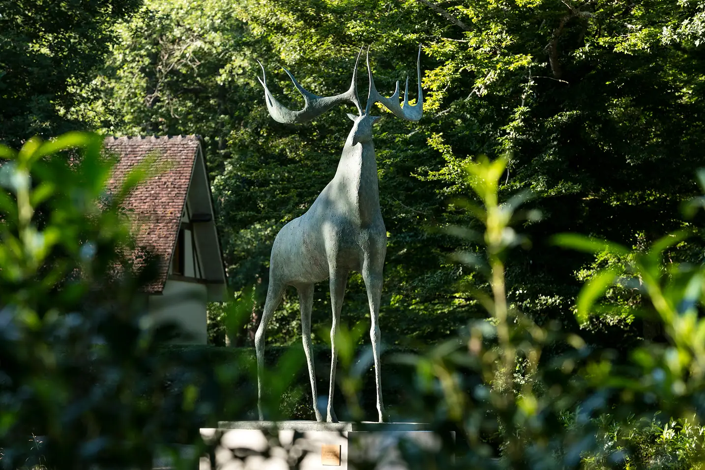 Statue of a deer standing with large antlers in a garden with a house in the background, Les Hauts de Loire, 5-star luxury hotel in Veuzain-sur-Loire, Loire Valley, France.