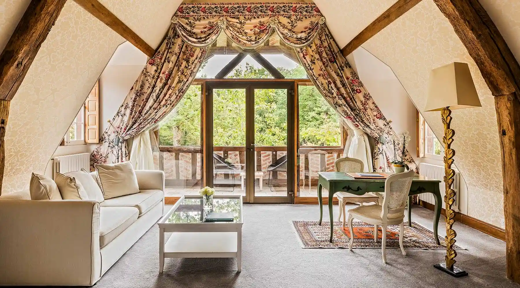 Les Hauts de Loire — Hotel, Restaurant & Spa — 5 stars: View of the attic lounge with cream sofa, glass coffee table, green desk and floral curtains.