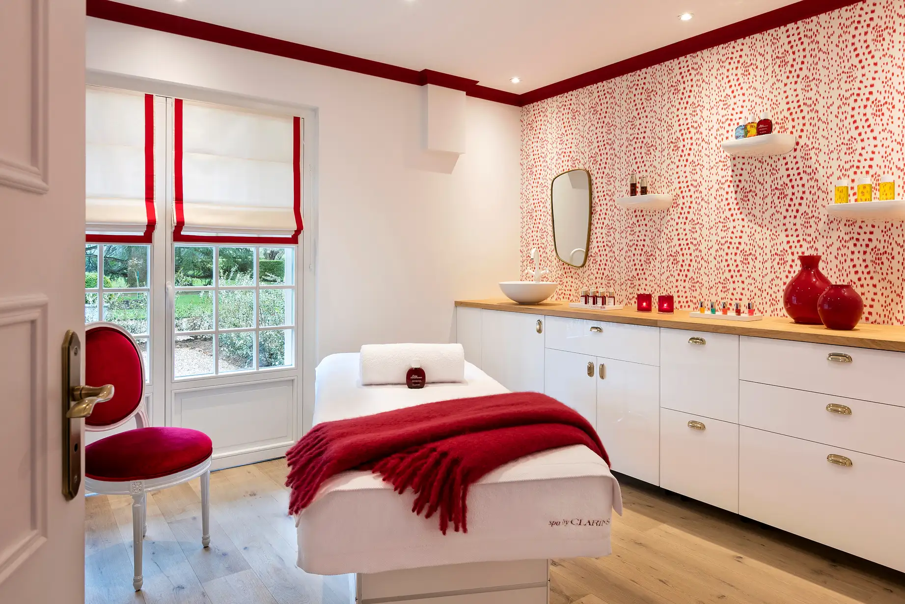 Les Hauts de Loire spa treatment room — Hotel, Restaurant & Spa — 5 stars, with a massage table, a red chair and a warm decor in red and white tones.