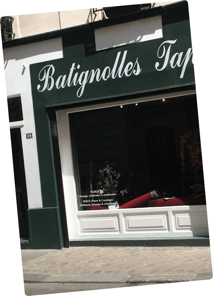 Devanture de magasin avec enseigne verte 'Batignolles Tap' et vitrine avec tapis roulés.