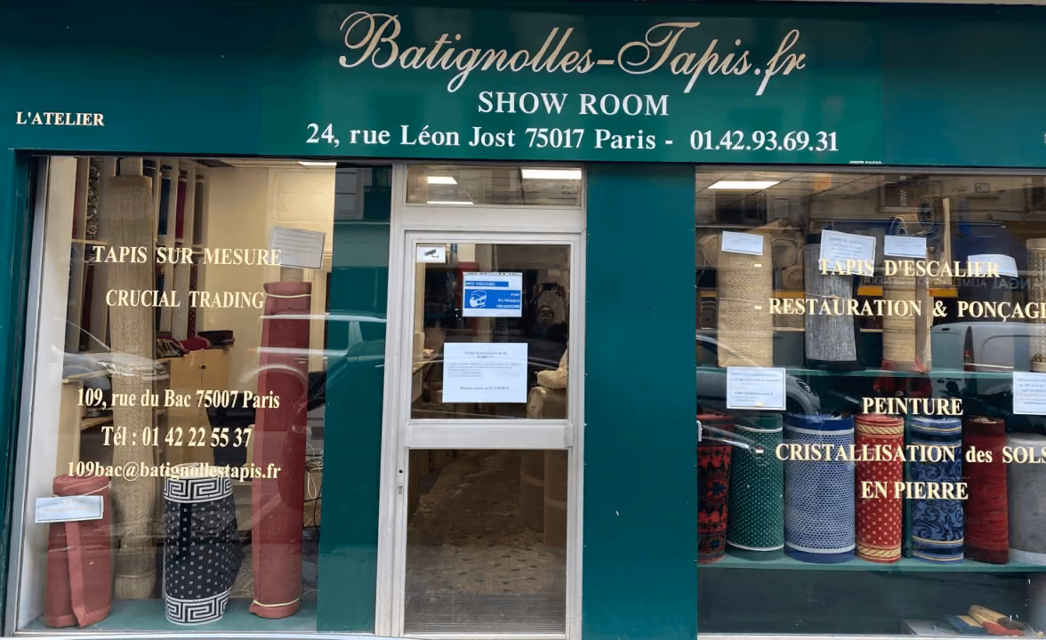 Devanture de Batignolles-Tapis avec tapis roulés exposés et coordonnées de showroom à Paris.