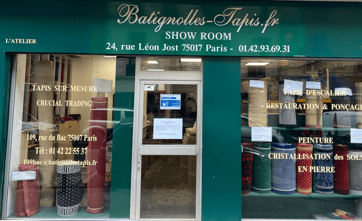 Devanture de Batignolles-Tapis avec tapis roulés exposés et coordonnées de showroom à Paris.