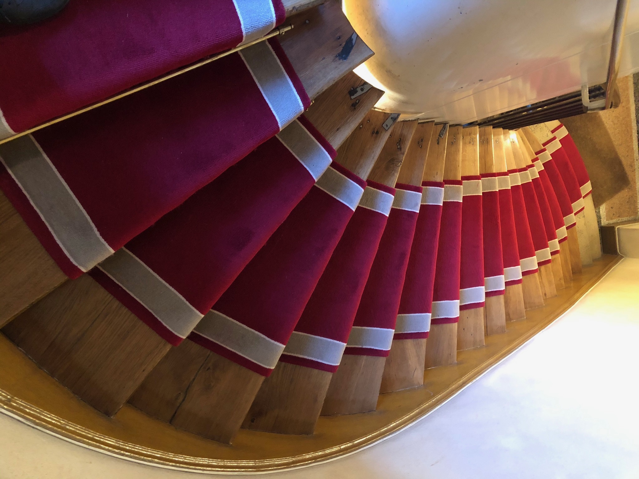 Détail du nez de marche d'un escalier en moquette posée collée.