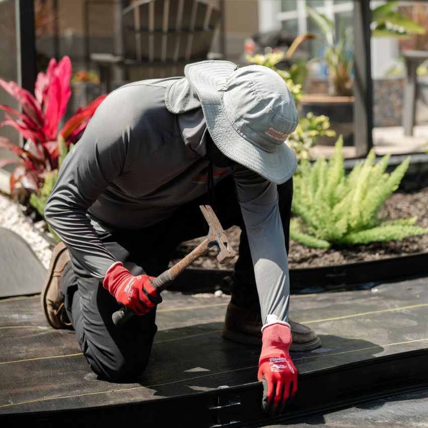 Sure Shot team member installing landscape edging around a newly planted bed.