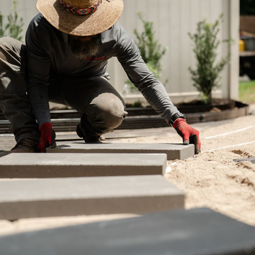 Team member positioning a rectangular stepping stone during pathway installation.