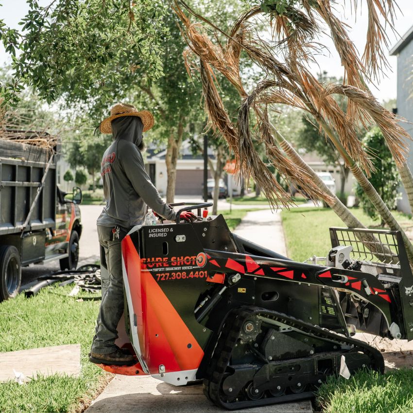 Sure Shot team member operating equipment during landscape site preparation.