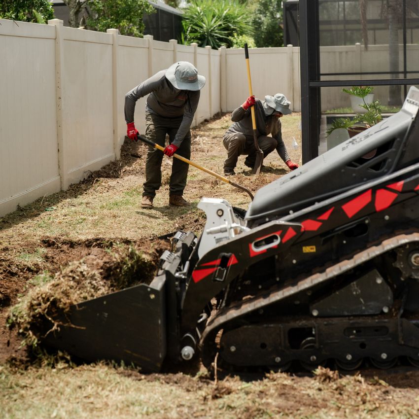 Sure Shot crew excavating and preparing a backyard landscape area with equipment.