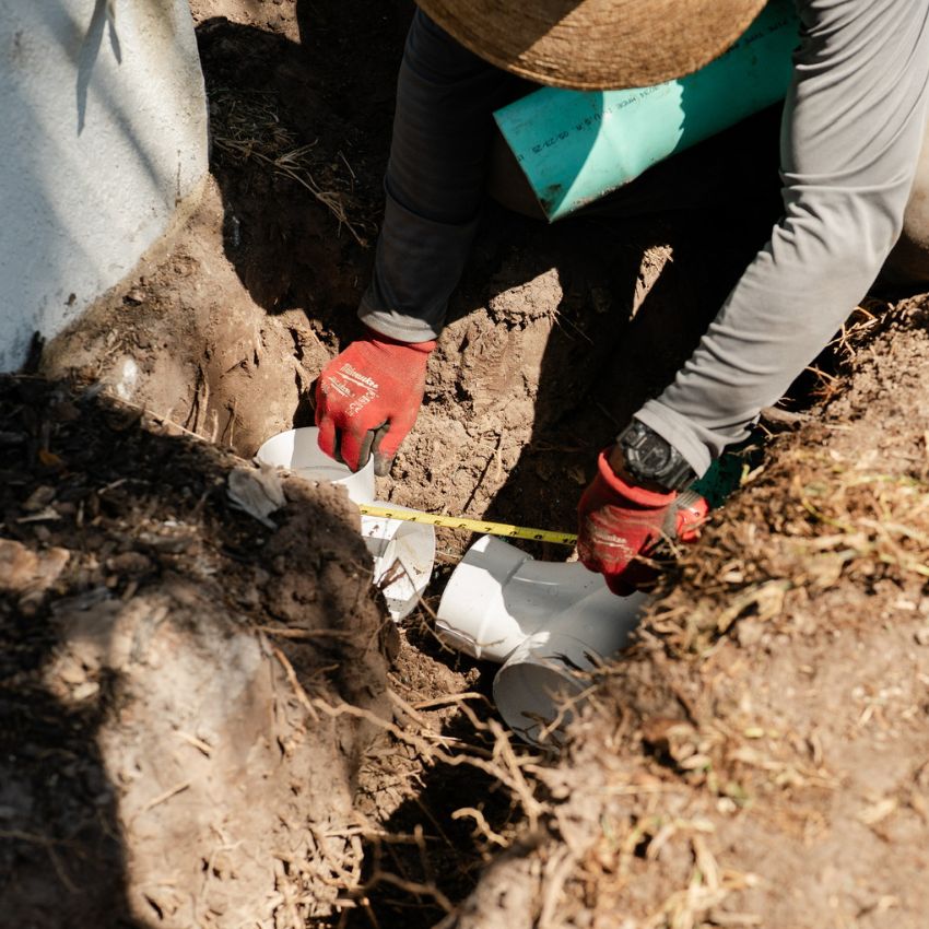 Sure Shot team member installing drainage pipe during the landscape project.