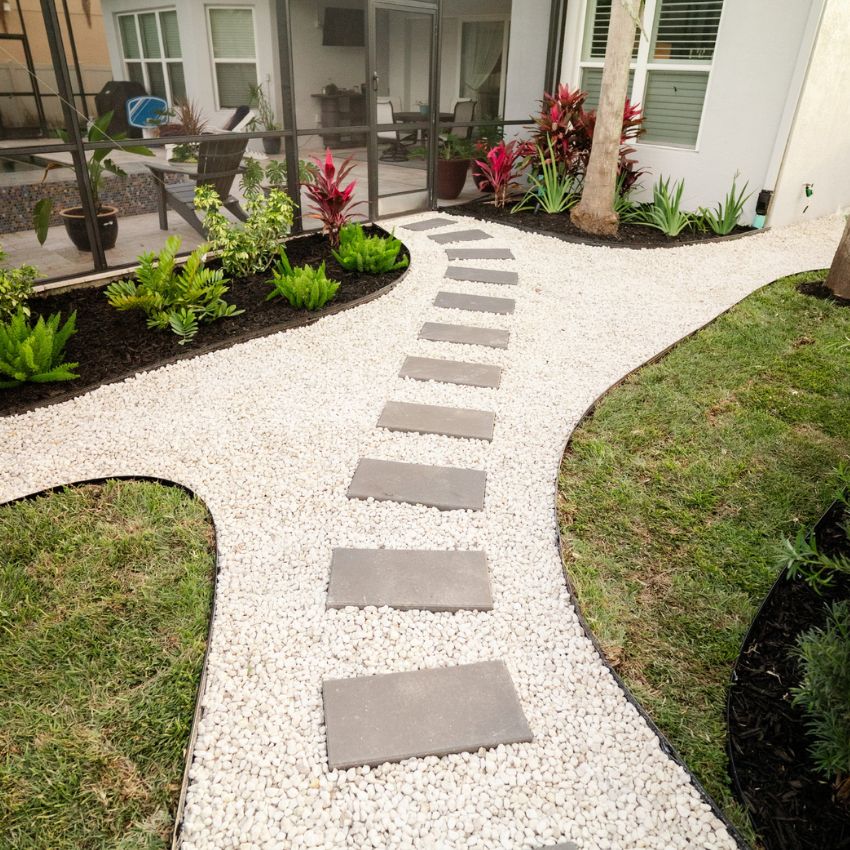 Finished curved walkway with white decorative stone and rectangular stepping stones.