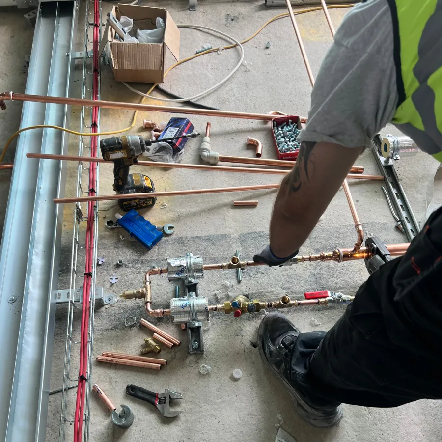 Engineer installing copper pipework for a commercial heating and mechanical services system.