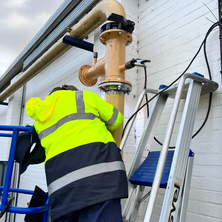 Engineer installing commercial gas pipework on an external industrial building.