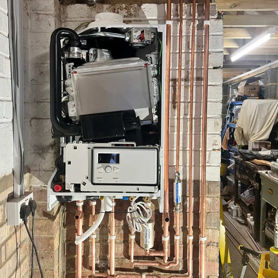 Wall-mounted condensing boiler installation with neatly routed copper pipework and heating system connections.
