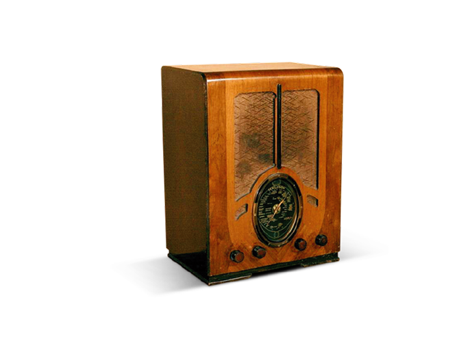 Vintage wooden tabletop radio with round dial and knobs on black background.