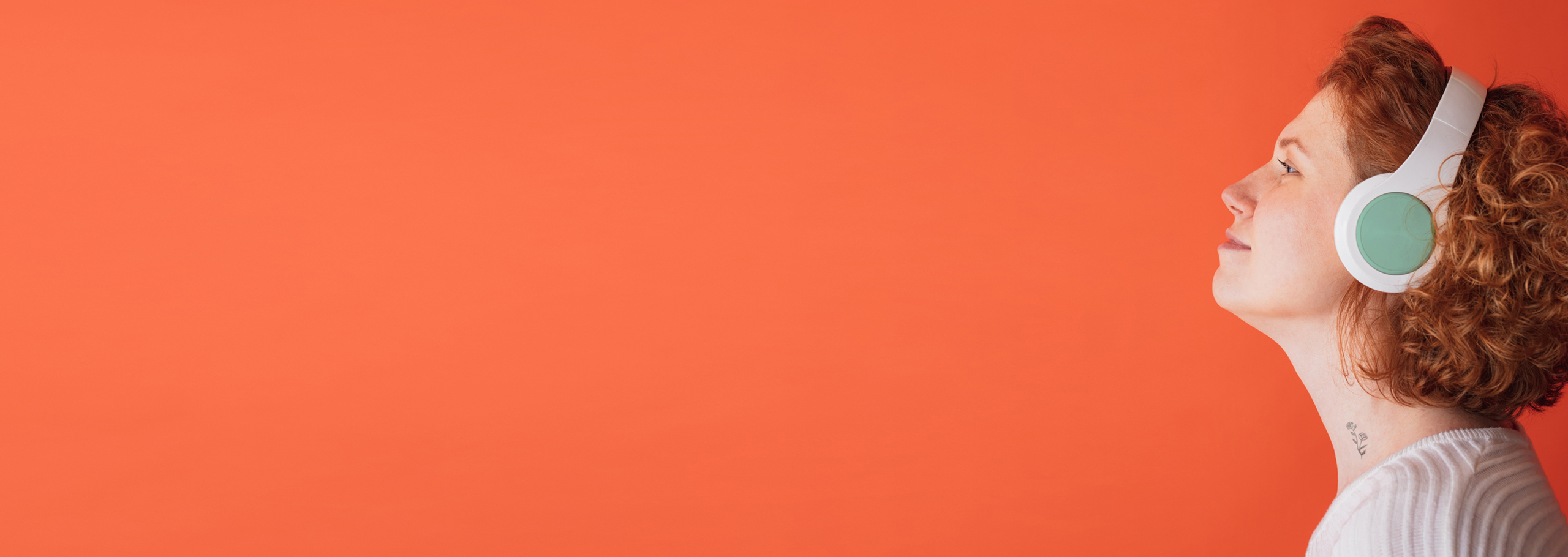 Profile of a woman with curly hair wearing white headphones against an orange background.