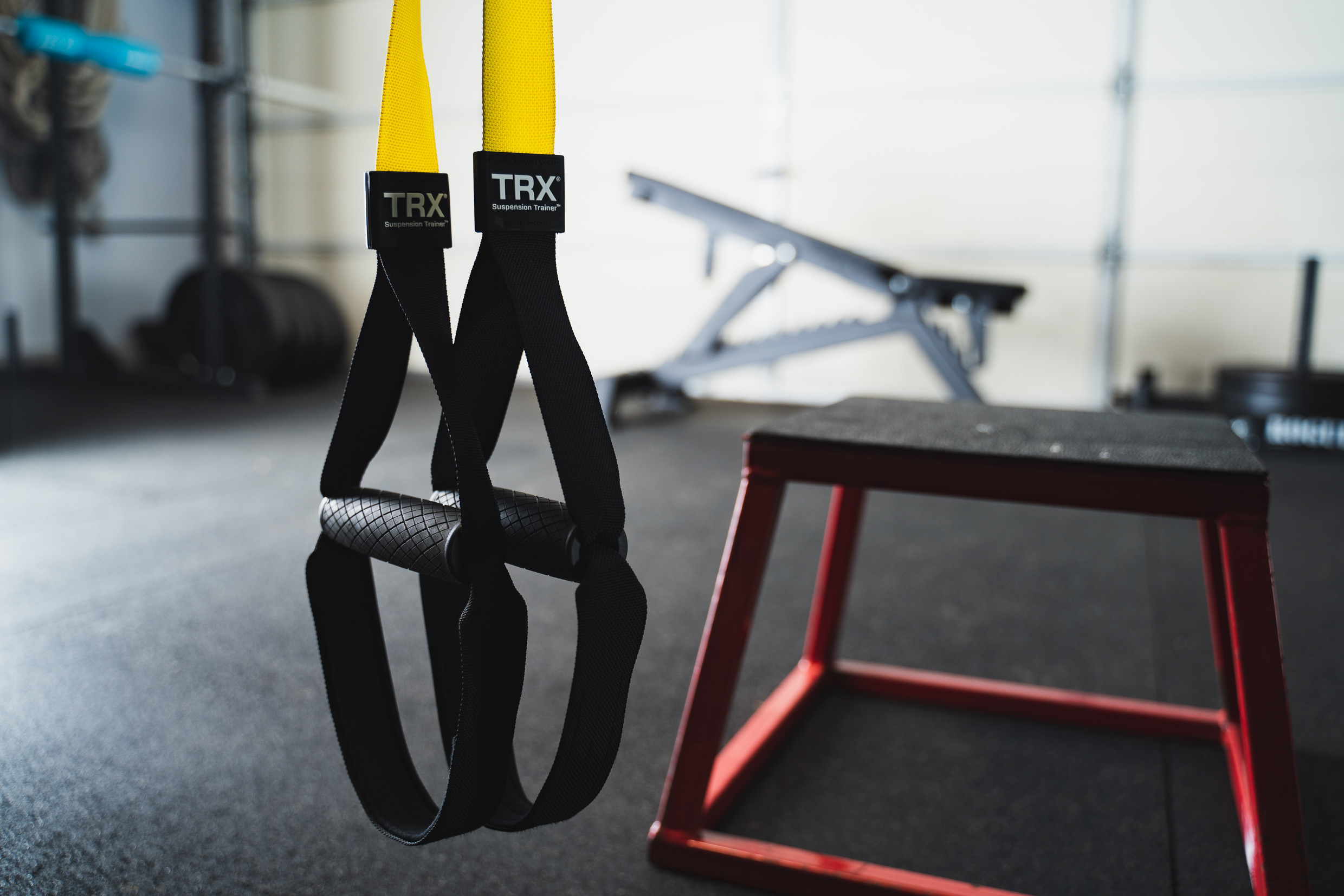TRX Suspension Trainer hanging straps with yellow and black handles in the gym