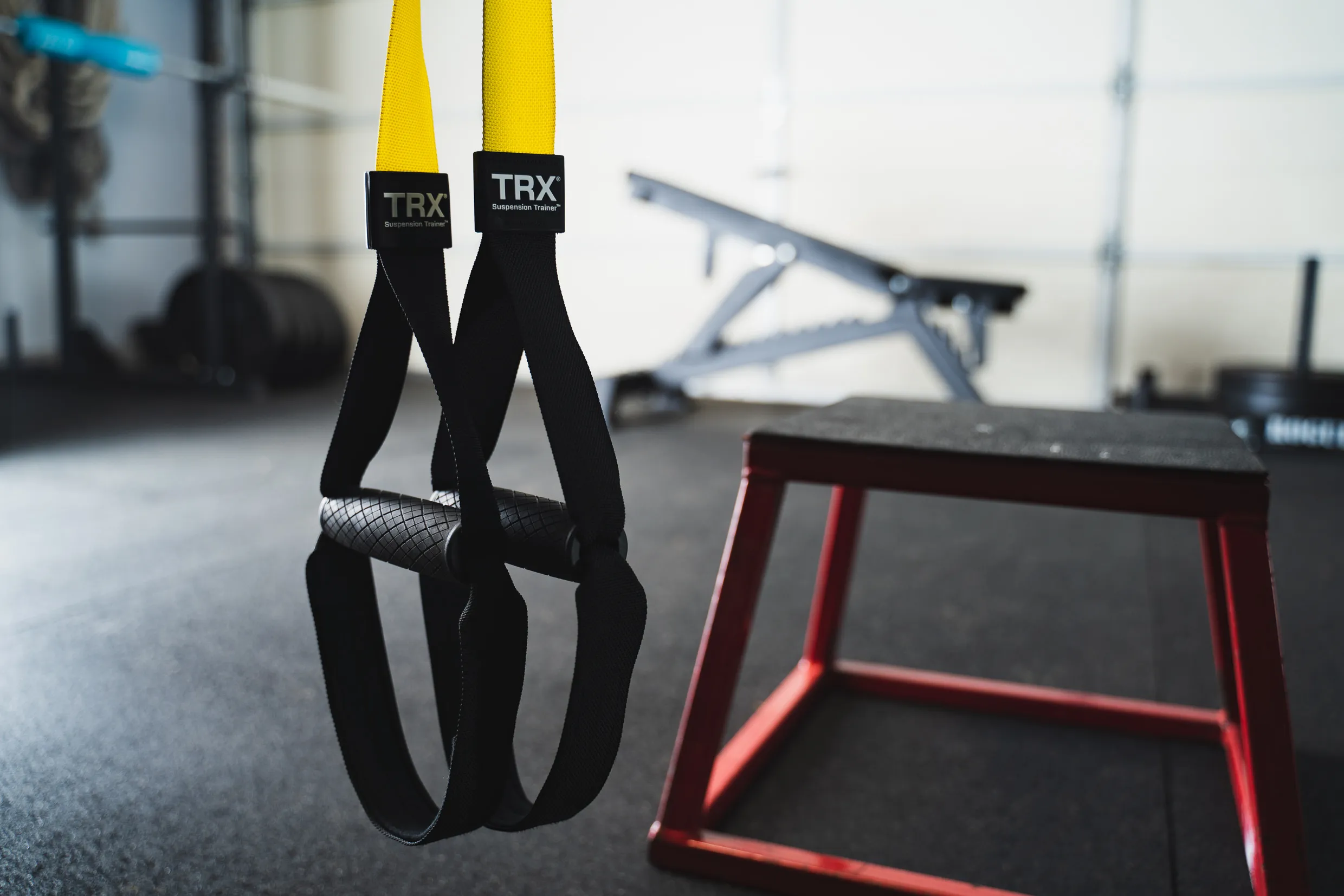 TRX Suspension Trainer hanging straps with yellow and black handles in the gym