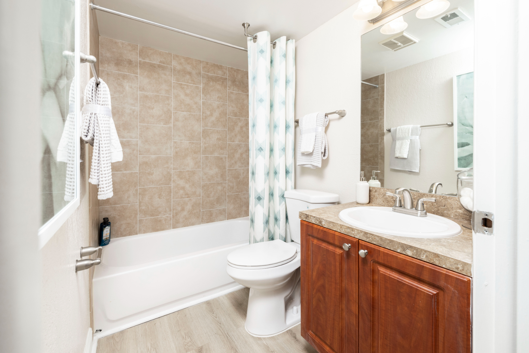 Bathroom with shower tub combo and brown cabinets