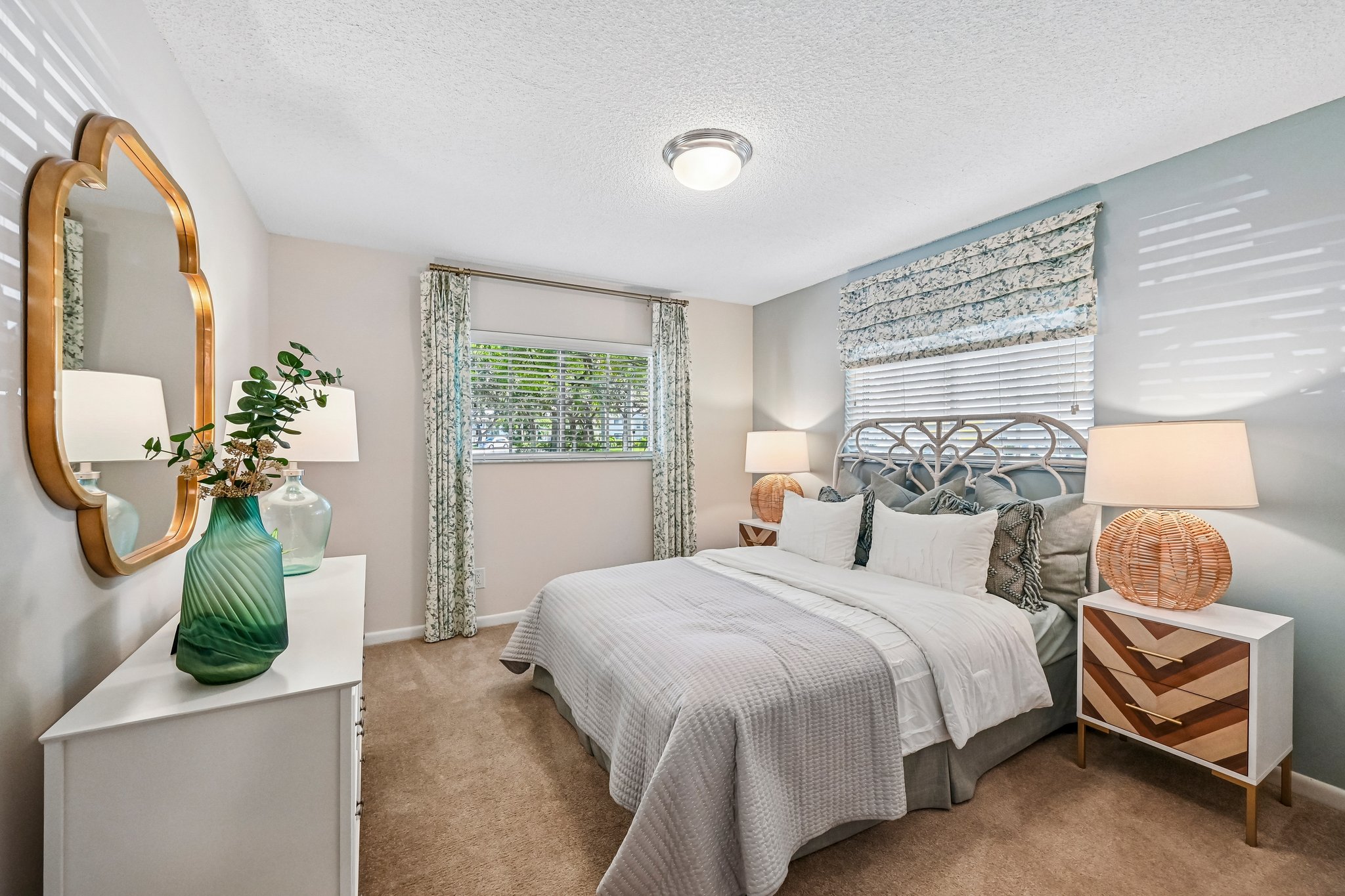 Bedroom with blue accent wall, dresser, and large bed Azalea Village