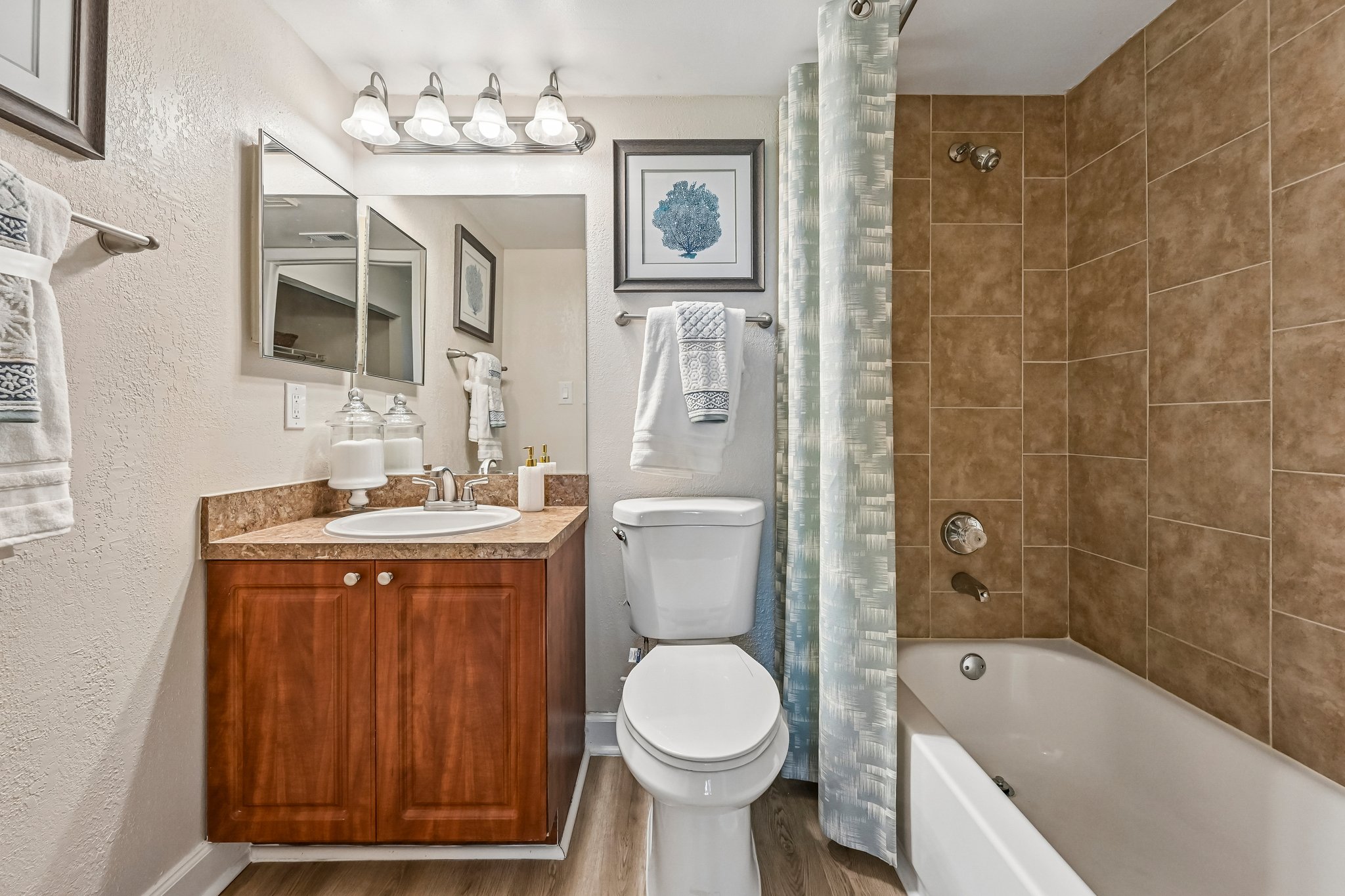 Bathroom with shower tub combo and brown cabinets Azalea Village