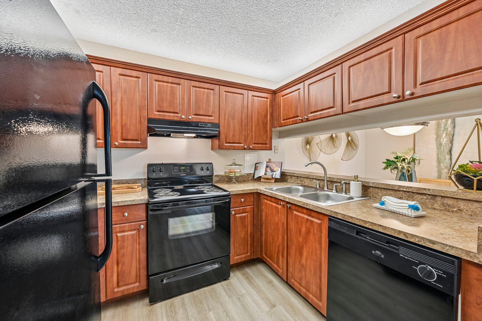 Kitchen with brown cabinets and black appliances Azalea Village