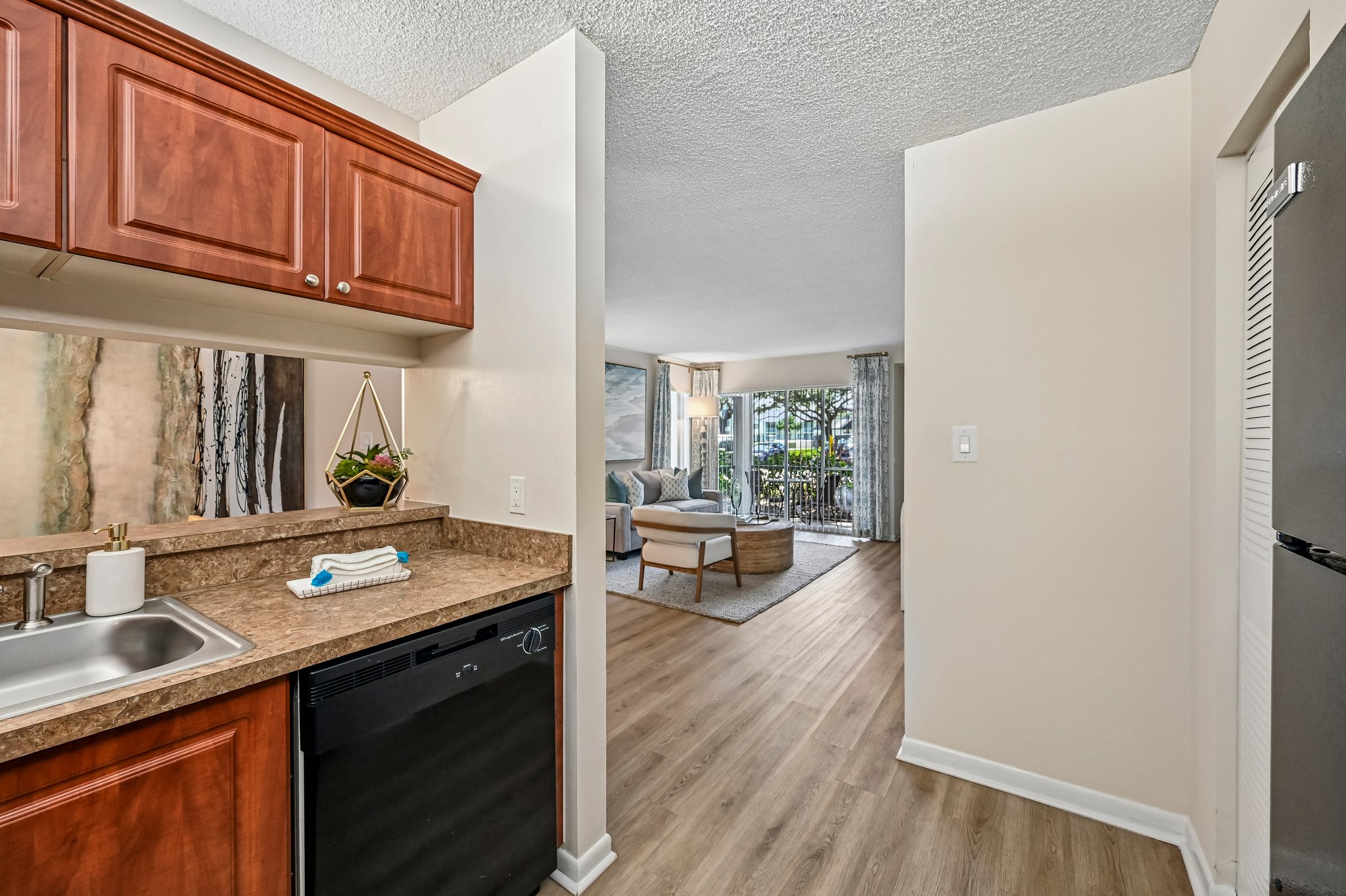 Kitchen with brown cabinets and black appliances and view of living room Azalea Village