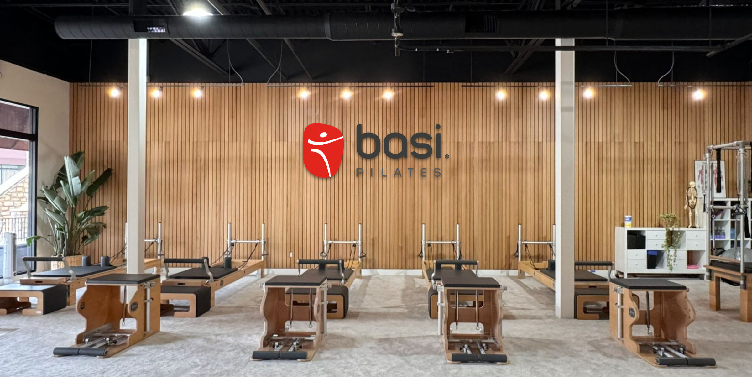 BASI Pilates El Dorado Hills studio interior with reformers and the BASI Pilates logo wall